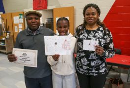 student with parents holding drawing of snowman