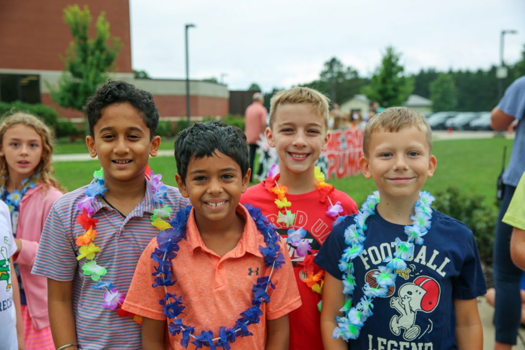 four elementary age boys wearing leis outside on the playground