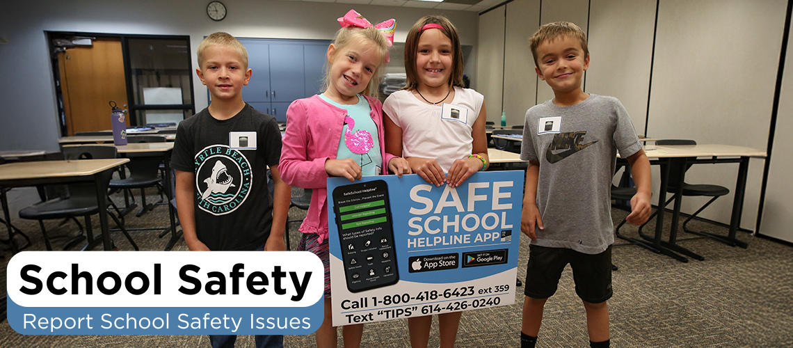 Four children standing together in what appears to be a classroom or office setting.