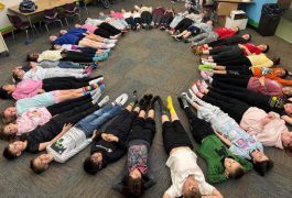 Children sitting on the floor in a circle, forming a human circle.