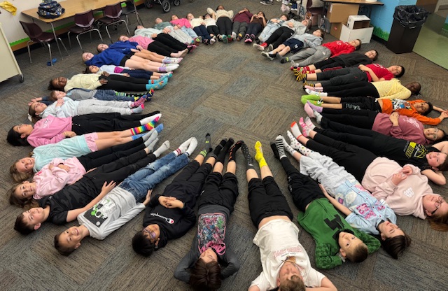 Children sitting on the floor in a circle, forming a human circle.
