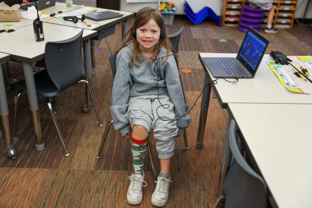 Smiling girl in classroom with bright socks.