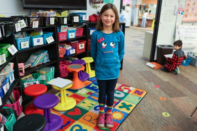 Smiling girl in classroom with bright socks.