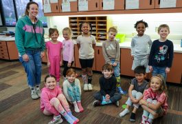 Students seated in a classroom, looking towards the front where an instructor is standing.